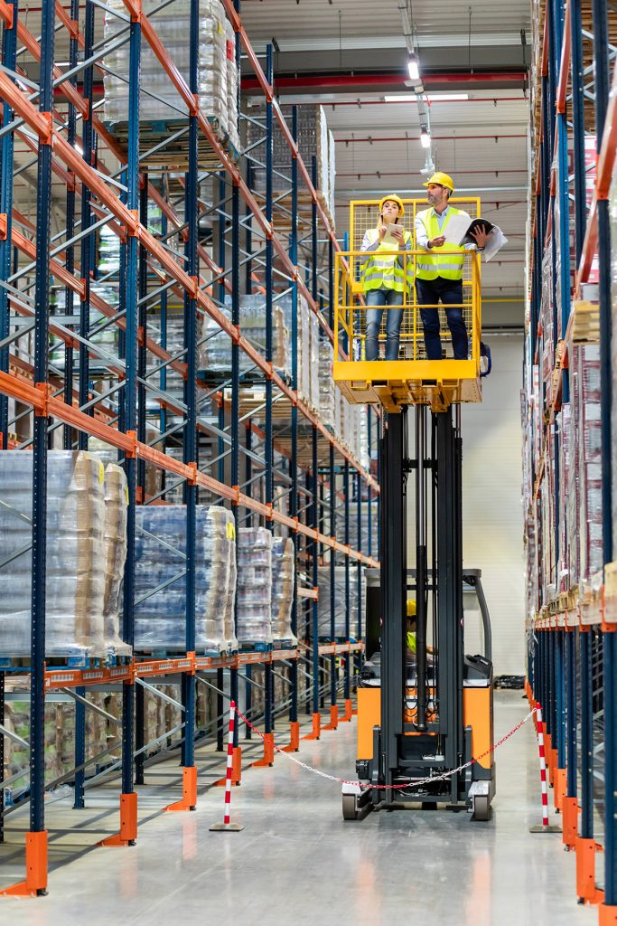 Warehouse workers using a lift to check inventory.