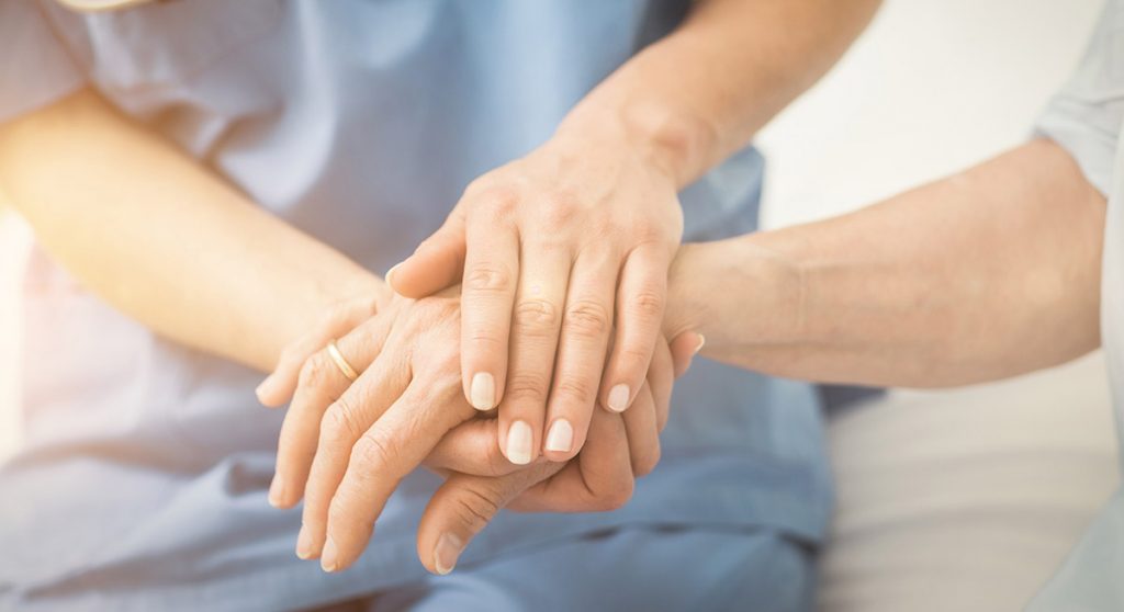 A Nurse holding their patient's hand.