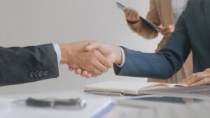 Employer recruiter hand shake with candidate with resume in job interview.