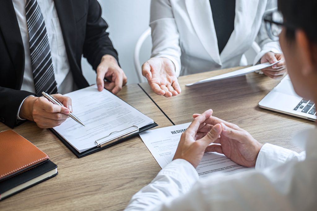 Employer or committee holding reading a resume with talking during about his profile of candidate, employer in suit is conducting a job interview, manager resource employment and recruitment.