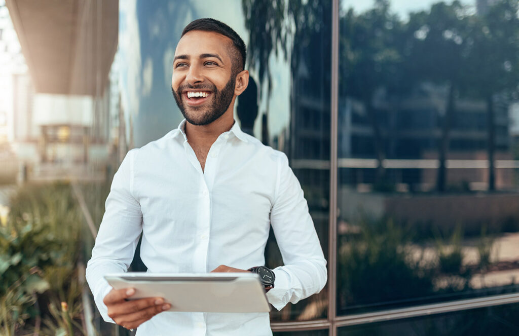 Portrait of a young confident smiling man holding a tablet.
